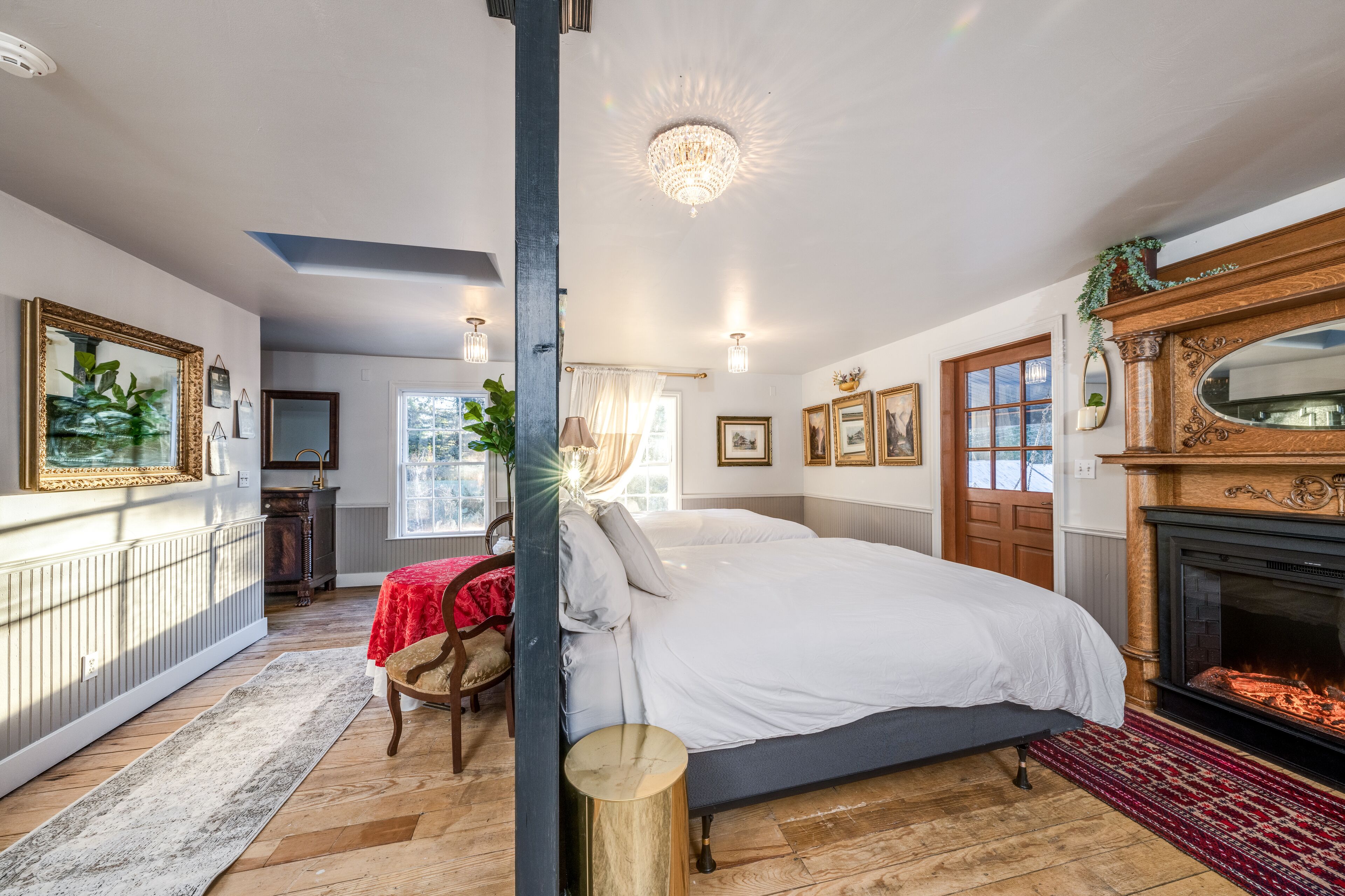 A bedroom with a large bed, a fireplace, and a view of the outdoors.
