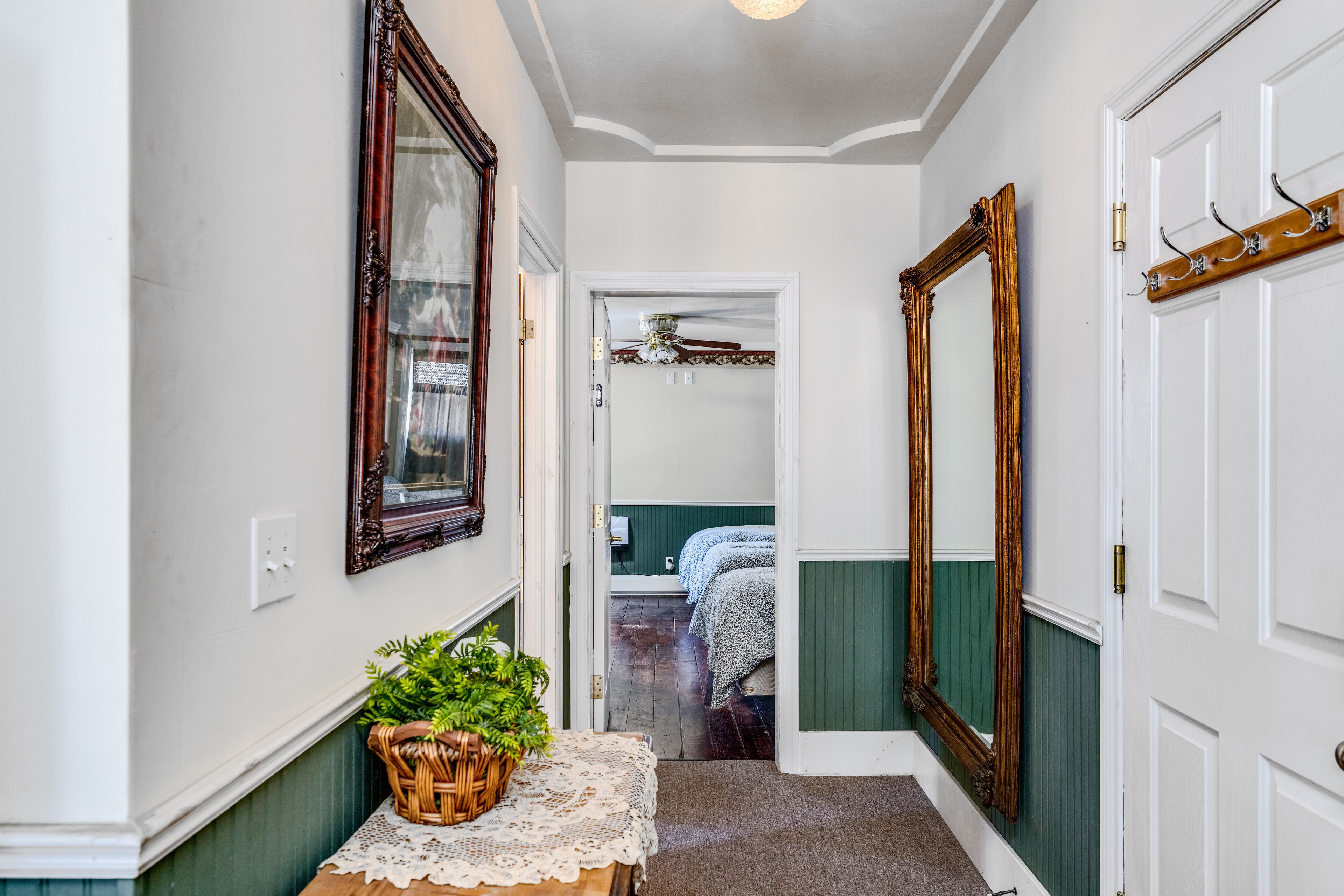 A hallway with a wicker basket on a table, a ceiling fan, and a door leading to a bedroom.