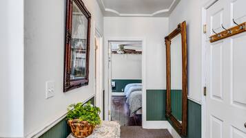 A hallway with a wicker basket on a table, a ceiling fan, and a door leading to a bedroom.