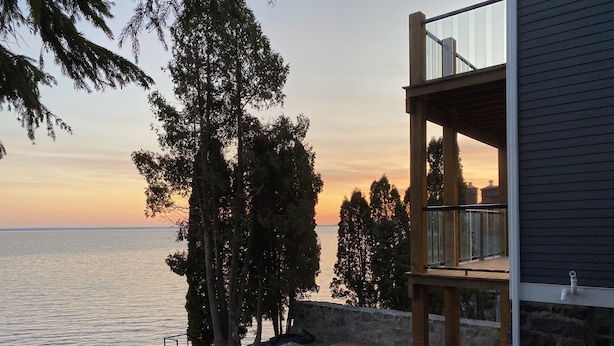 A coastal property with a stone retaining wall, a wooden deck, and a balcony overlooking the sea. - The Gales on Lake Superior  I  Stunning Lakeshore & Views  I  by Relax Open Air (Duluth)