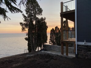 Ein Küsteneigentum mit einer Steinmauer, einer Holzterrasse und einem Balkon mit Meerblick.