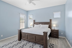 A bedroom with a wooden bed, two bedside tables with lamps, and a ceiling fan.