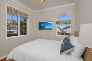 Relax in a spacious bedroom with a large bed, TV, and scenic views from the windows.
