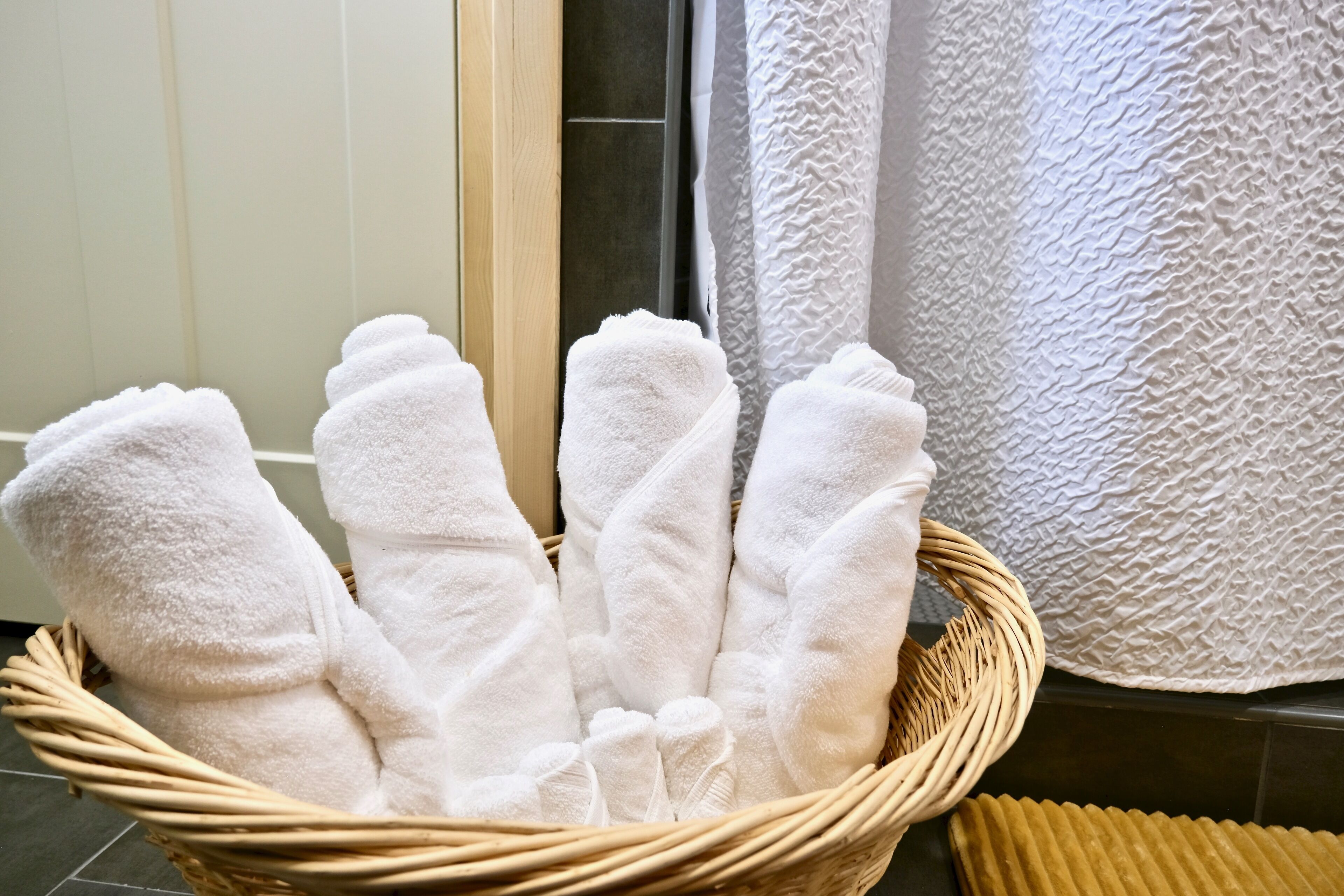 A wicker basket filled with white towels in a bathroom setting.