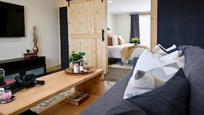 Une chambre d’hôtel moderne avec un bureau en bois, un canapé et un lit donnant sur une vue agréable.