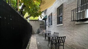 An outdoor seating area with tables and chairs, a stone wall, and string lights.