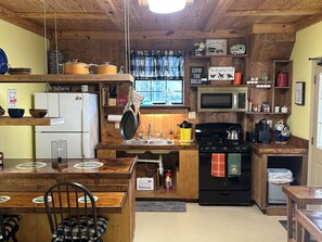 Une cuisine rustique avec des murs en bois, un réfrigérateur, une cuisinière, un évier et divers ustensiles de cuisine.