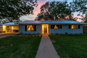A single-story house with a front porch, a visible garage door, and a number '610' on the front wall. - Fall Wine Escape - Walk to Main - GameRm + Hot Tub (Fredericksburg)