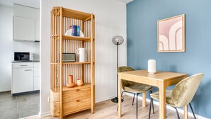 A modern kitchen with white cabinets, a microwave, and a wooden bookshelf. - Sleek Iselin 2 Room w/ Storage, 1min to Local Market, by Blueground (Basel)