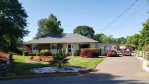 A residential street with houses, a driveway, and a red car parked on the street. - Bright & Spacious Studio Close To CLT Airport & Charlotte (Gastonia)