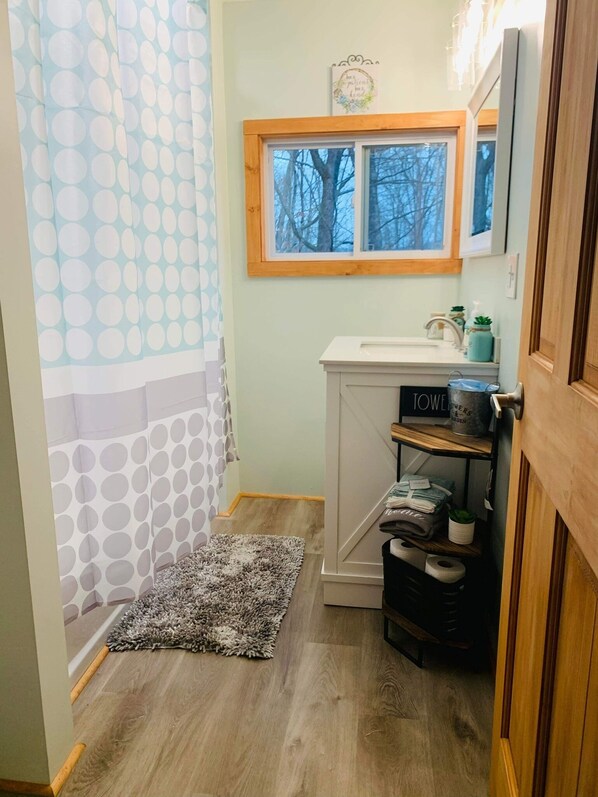 Un bagno piccolo con tenda doccia, una finestra, un lavandino e un portasciugamani.