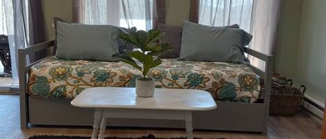 Una habitación acogedora con una cama, una mesita y una planta en maceta.