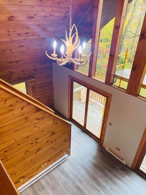 Un interno in legno con un lampadario, ampie finestre e vista sull'esterno.