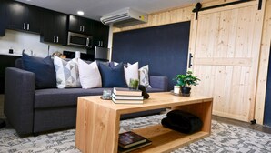 A modern living room with a grey sofa, wooden coffee table, and a large wooden door.