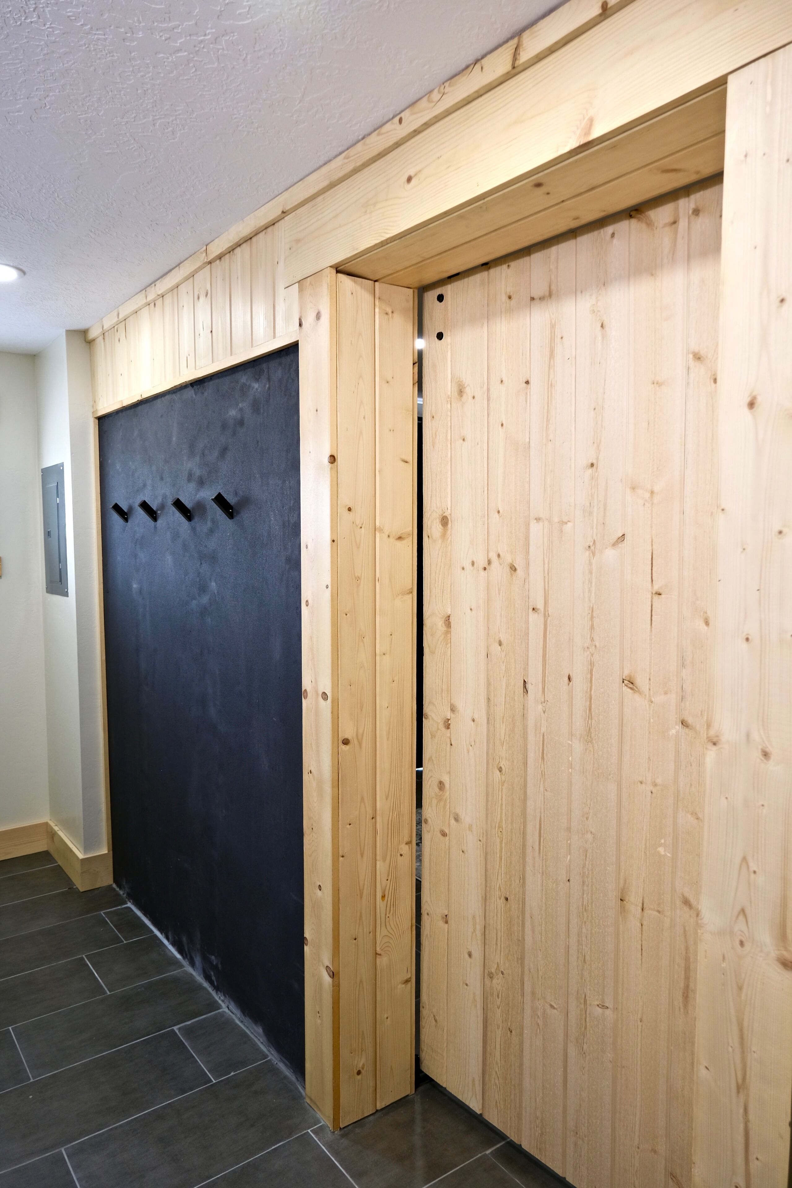 A hallway with a wooden door and a black door.
