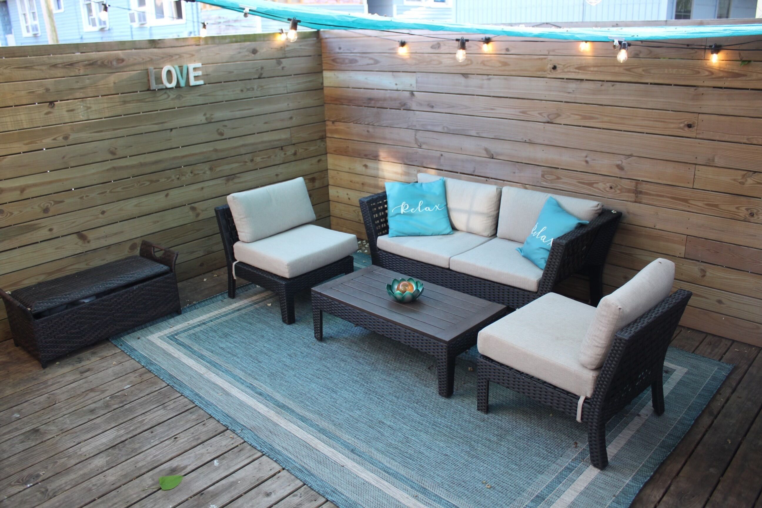 An outdoor patio area with wicker furniture, a coffee table, and a wall with the word "LOVE".