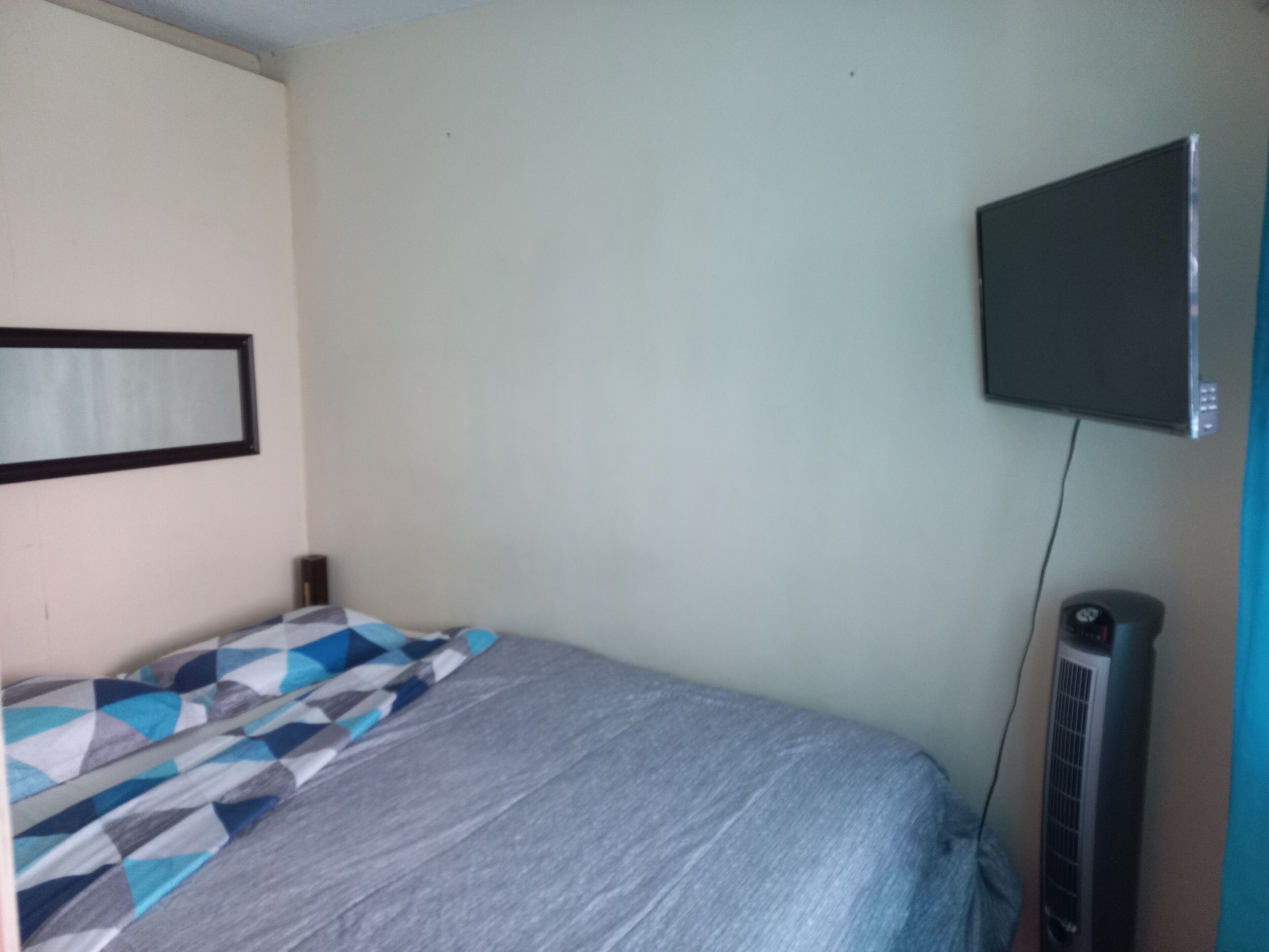 Ein Schlafzimmer mit einem Bett, einem an der Wand befestigten Fernseher und einem Heizkörper.