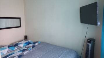 Ein Schlafzimmer mit einem Bett, einem an der Wand befestigten Fernseher und einem Heizkörper.