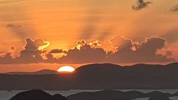 Ein Sonnenuntergang über einem Gewässer mit weitergehendem Land in der Ferne.