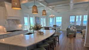 A spacious kitchen with a large island, pendant lighting, and a view to the outside.