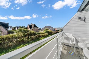 Un balcon donnant sur un quartier résidentiel, avec vue sur des maisons et un espace verdoyant.