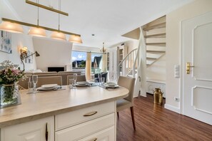 Un interior moderno con zona de comedor, una escalera y vistas a través de una ventana.