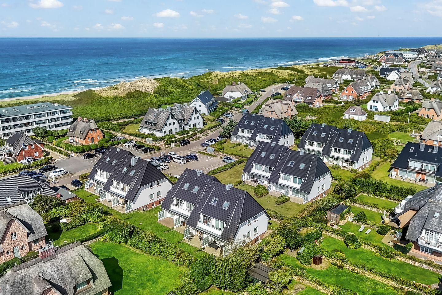 A coastal residential area with houses, a beach, and a clear sky.