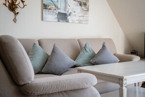 A modern living room with a beige sofa, a white coffee table, and a painting on the wall.