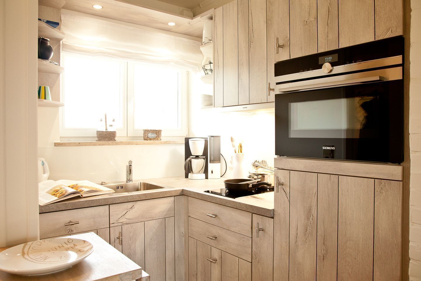 A modern kitchen with wooden cabinets, a built-in oven, and a coffee maker.
