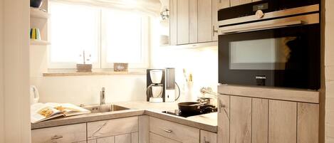 A modern kitchen with wooden cabinets, a built-in oven, and a coffee maker.