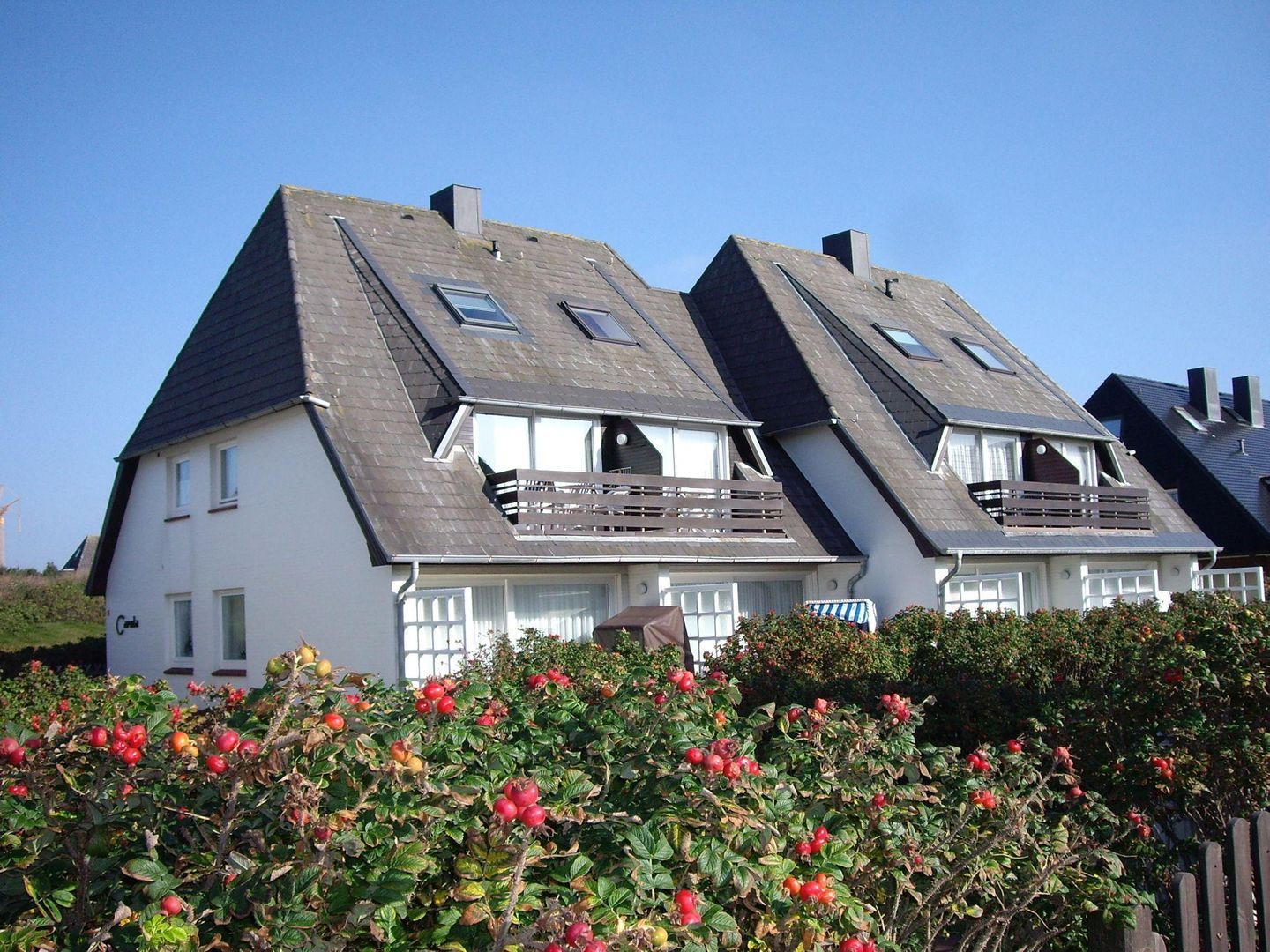 A row of white houses with steeply pitched roofs and wooden balconies.