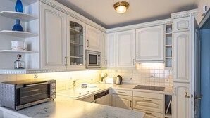 Une cuisine moderne avec des meubles blancs, un four à micro-ondes encastré, un grille-pain et un évier.