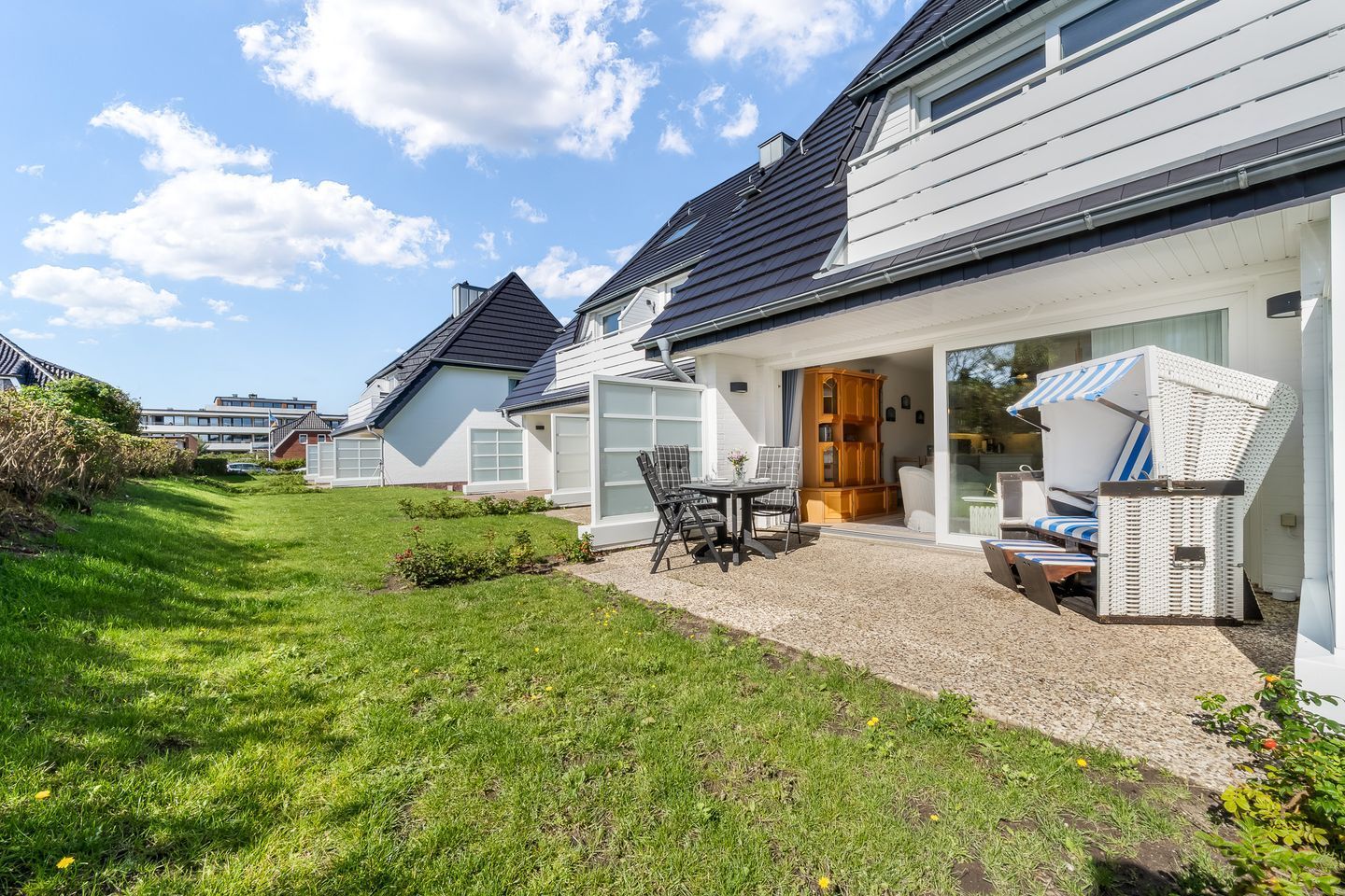A residential property with a covered patio, outdoor seating, and a well-maintained lawn.