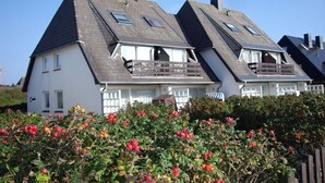 Une rangée de maisons blanches aux toits à forte pente et aux balcons en bois.