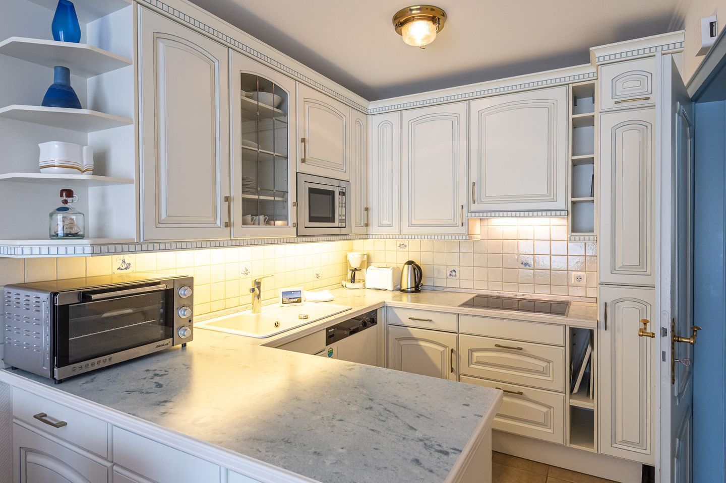 A modern kitchen with white cabinetry, a built-in microwave, a toaster, and a sink.