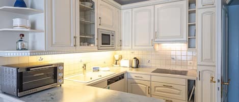 A modern kitchen with white cabinetry, a built-in microwave, a toaster, and a sink.