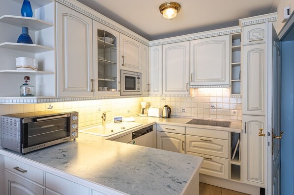 A modern kitchen with white cabinetry, a built-in microwave, a toaster, and a sink.