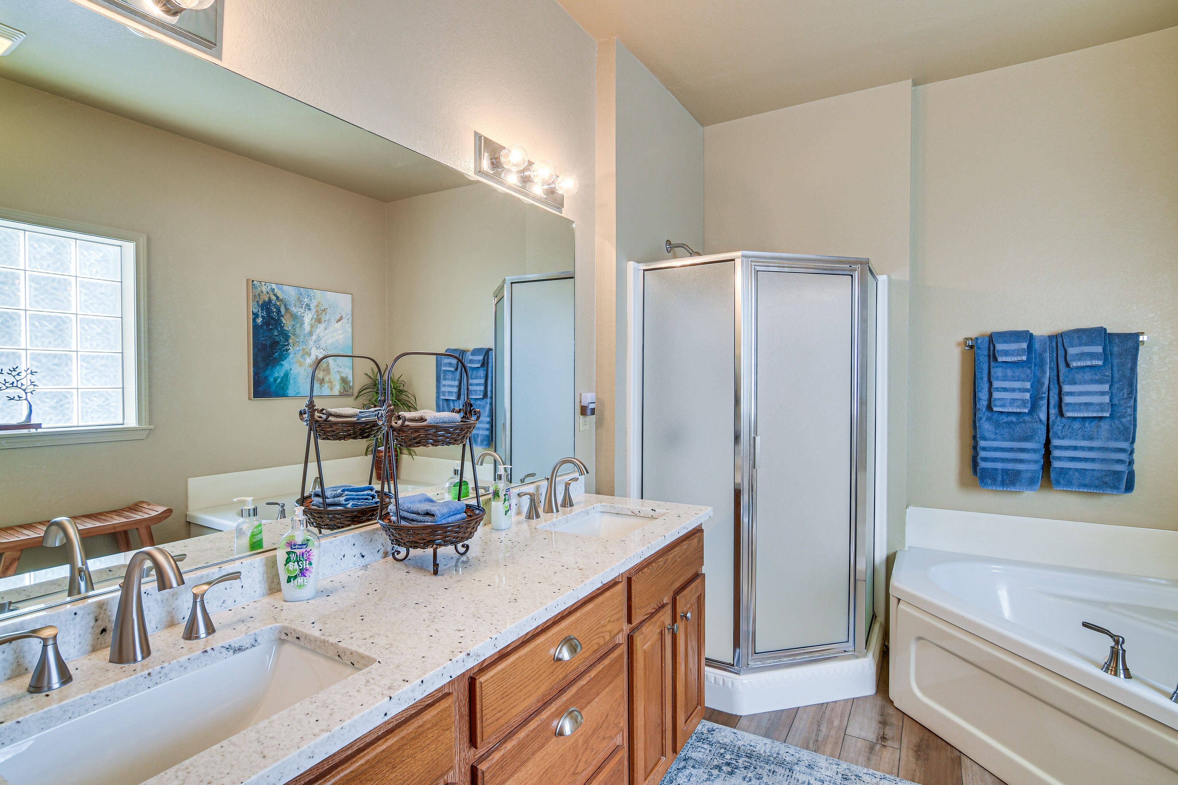 A bathroom with a large sink, a bathtub, a shower, and a mirror with lights.