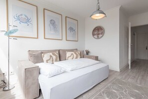 Un dormitorio con cama, mesita de noche, lámpara y cuadros en la pared.