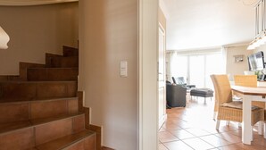 A staircase leading to a living area with a dining table and chairs.