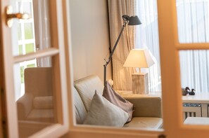 Et hyggeligt værelse med sofa, to lamper og udsigt ud af et vindue med gardiner.