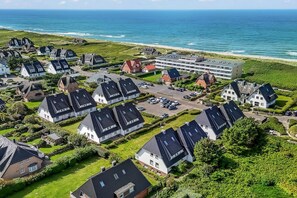 Une zone résidentielle côtière avec des maisons, un parking et une plage en arrière-plan.