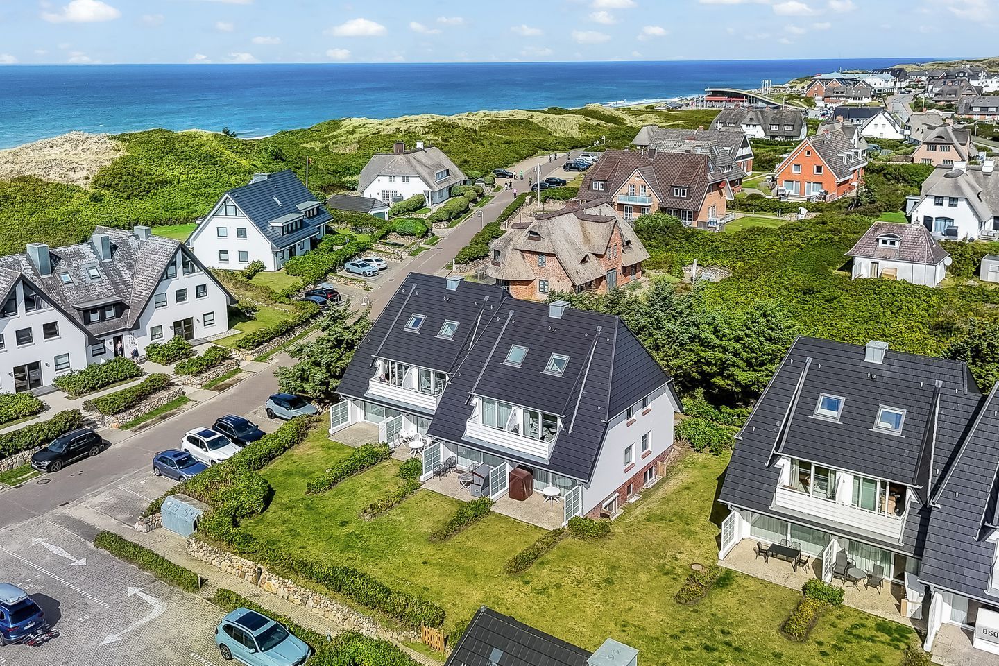 A residential area with houses, a road, and a view of the sea.