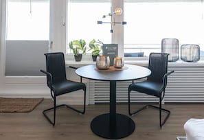 Un comedor moderno con dos sillas negras, una mesa redonda y elementos decorativos.