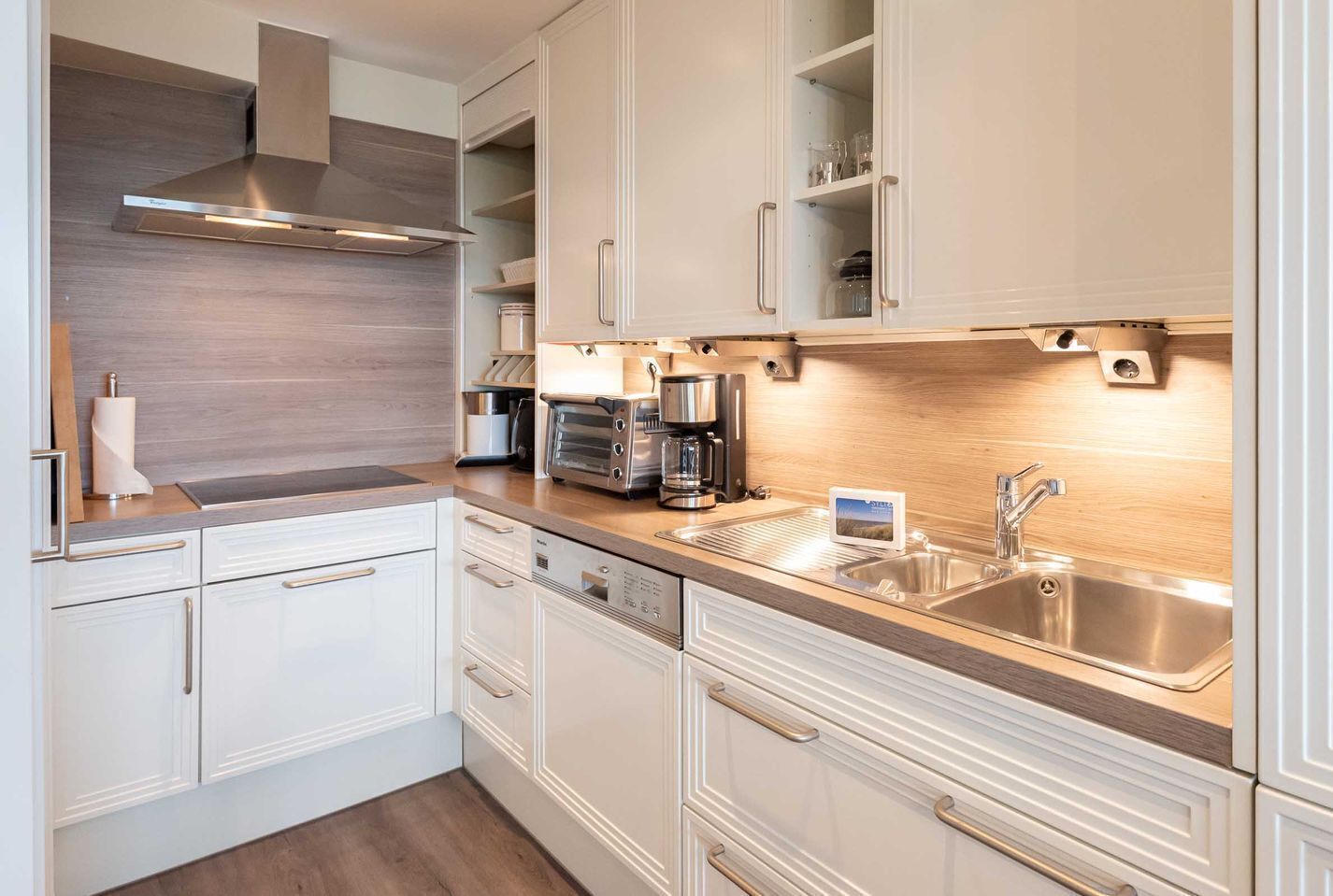 A modern kitchen with white cabinetry, stainless steel appliances, and a wooden countertop.