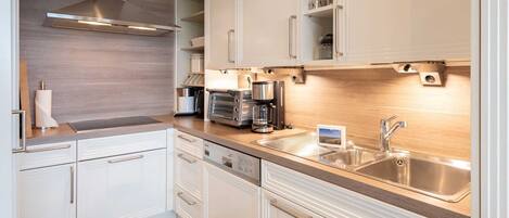 A modern kitchen with white cabinetry, stainless steel appliances, and a wooden countertop.