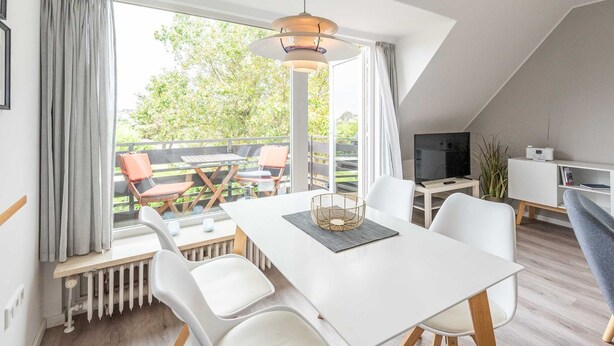 Ein modernes Wohnzimmer mit Essbereich, großen Fenstern und Blick ins Freie.