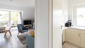 Eine moderne Küche mit Kaffeemaschine und Fernseher im Wohnbereich.