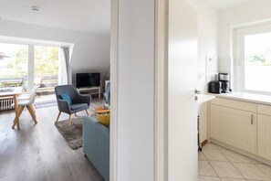 A modern kitchen with a coffee maker and a TV in the living area.
