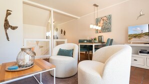 Un soggiorno moderno con un divano, un tavolo da pranzo, una TV e un elemento decorativo a parete.